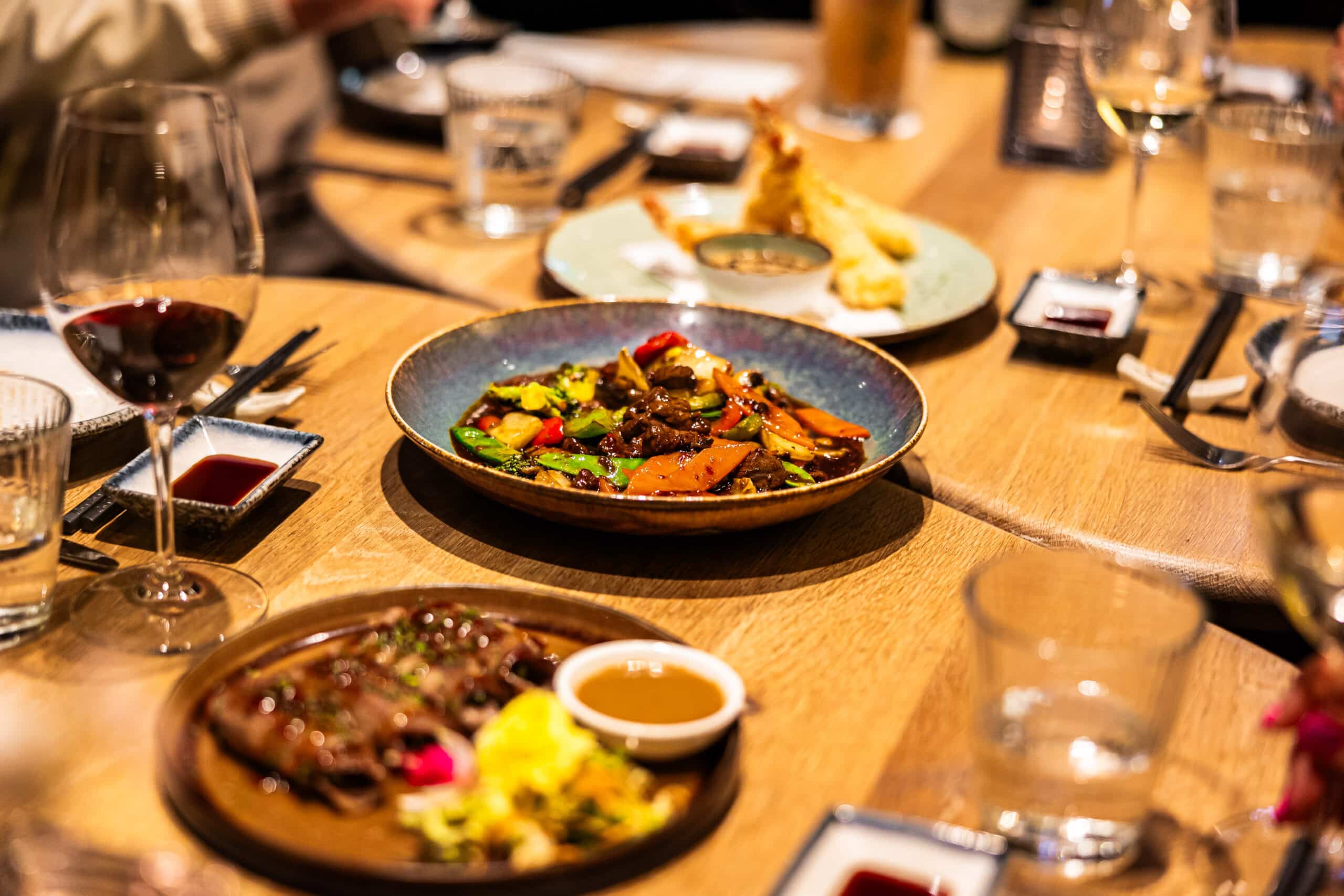 Diverse Aziatische gerechten op tafel met roerbak en tempura bij restaurant Yuzu in Enschede