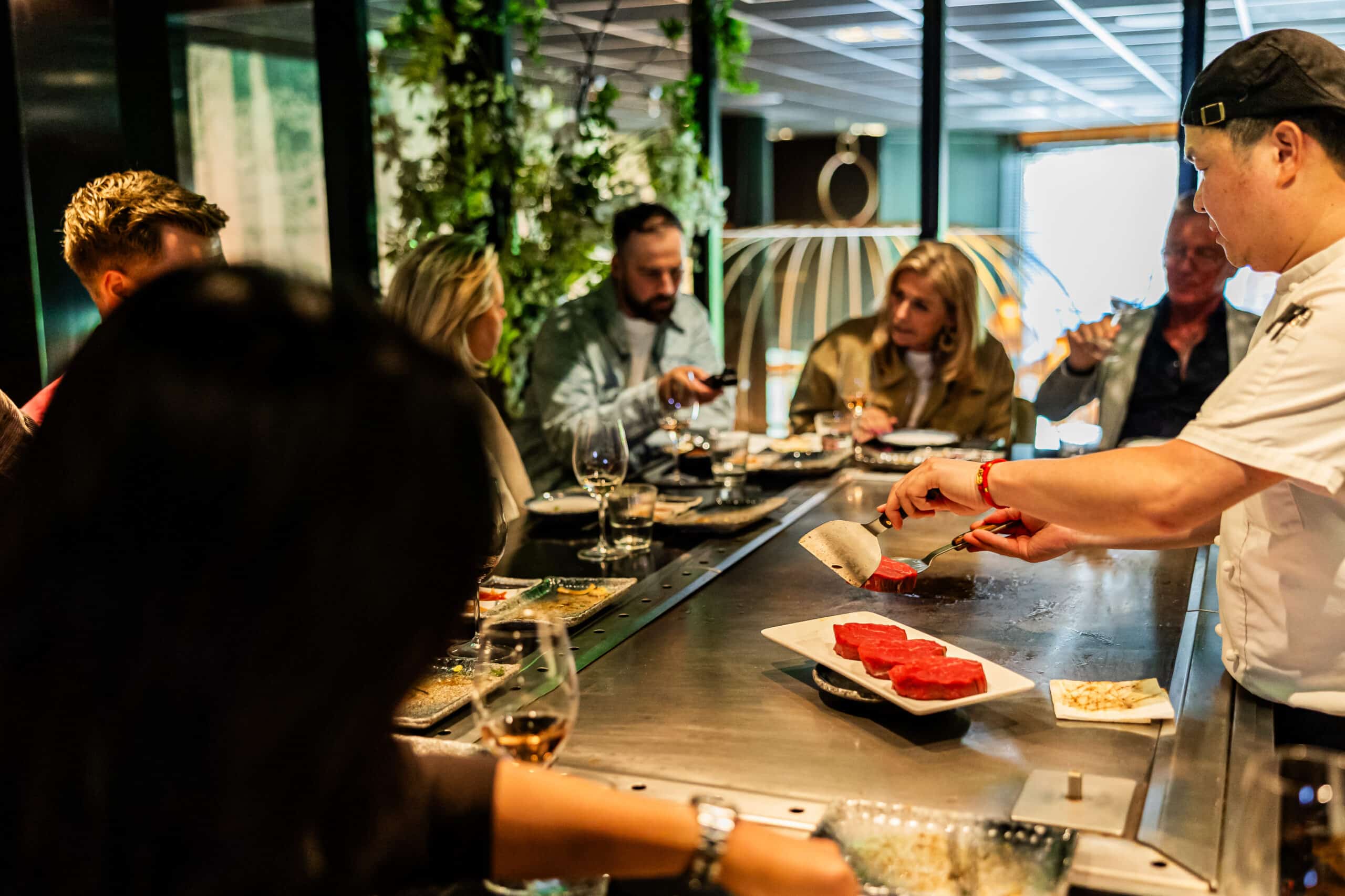 Gasten aan de teppanyaki-grill bij restaurant Yuzu in Enschede met vlammen boven de bakplaat